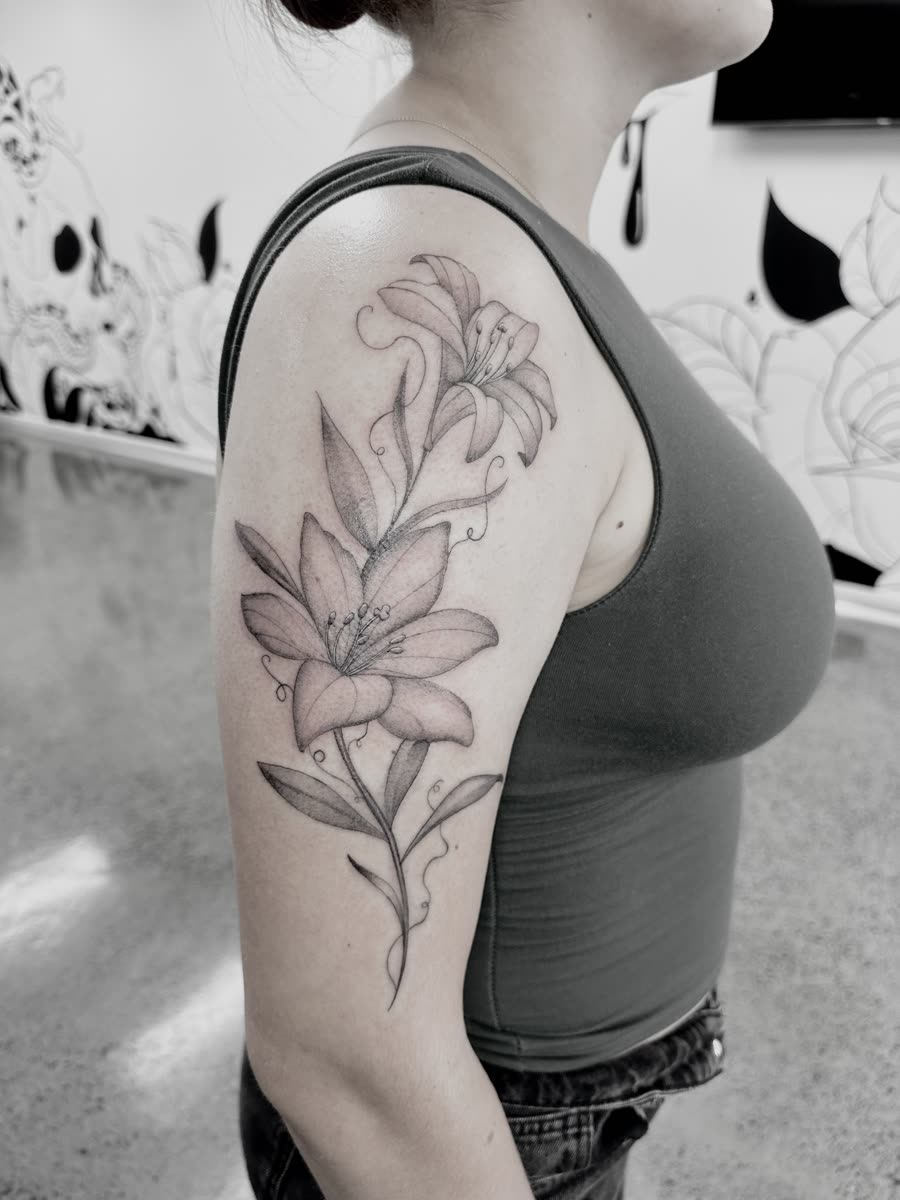 Twin lilies fineline tattoo on an upper arm